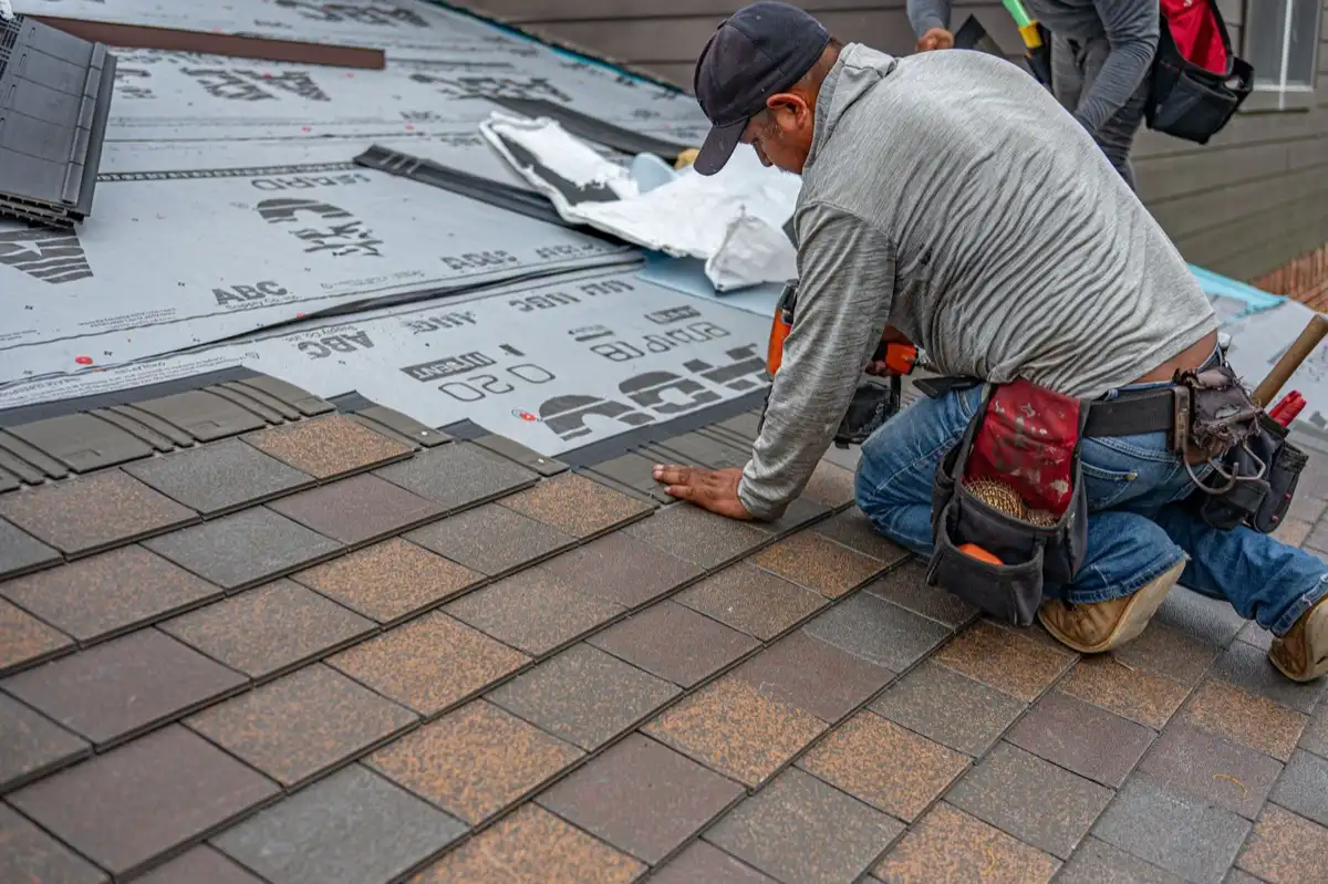 Roofing installer fastening shingles over new underlayment in Sunrise, FL